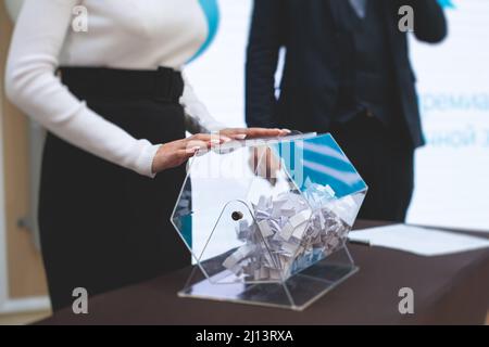 Processo di estrazione dei premi, estrazione di un numero vincente di lotteria macchina, tamburo di lotteria con bingo palle e vincita dei biglietti in occasione dell'evento con l'ospite e Foto Stock