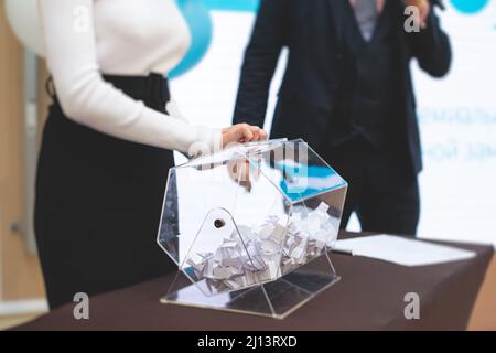 Processo di estrazione dei premi, estrazione di un numero vincente di lotteria macchina, tamburo di lotteria con bingo palle e vincita dei biglietti in occasione dell'evento con l'ospite e Foto Stock