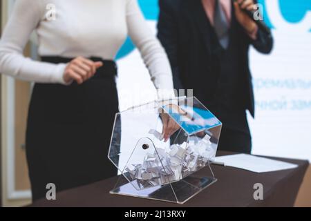 Processo di estrazione dei premi, estrazione di un numero vincente di lotteria macchina, tamburo di lotteria con bingo palle e vincita dei biglietti in occasione dell'evento con l'ospite e Foto Stock