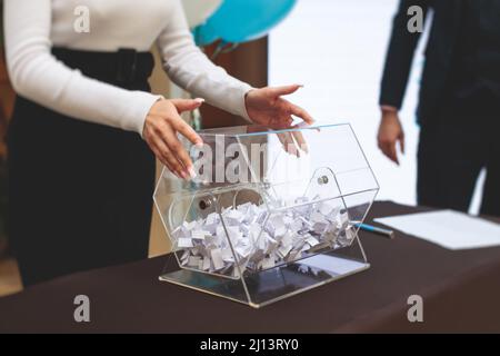 Processo di estrazione dei premi, estrazione di un numero vincente di lotteria macchina, tamburo di lotteria con bingo palle e vincita dei biglietti in occasione dell'evento con l'ospite e Foto Stock