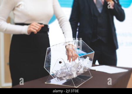Processo di estrazione dei premi, estrazione di un numero vincente di lotteria macchina, tamburo di lotteria con bingo palle e vincita dei biglietti in occasione dell'evento con l'ospite e Foto Stock