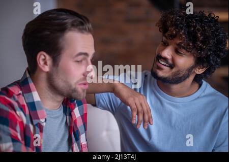 Coppia gay biraciale che ha una conversazione al chiuso Foto Stock