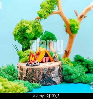 Campo turistico. Paesaggio plastificato con una tenda, un falò e uno zaino in mezzo alla foresta. Il concetto di eco-friendly ricreazione e envi Foto Stock