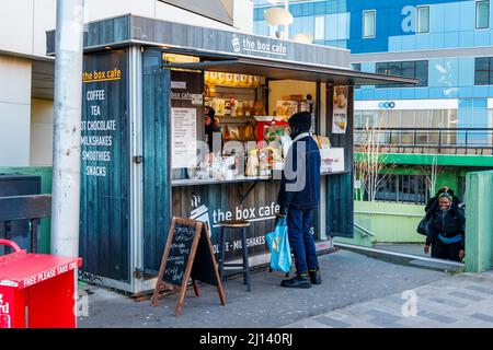 Un cliente al Box Cafe, una piccola capanna che offre bevande e spuntini fuori dalla stazione di Archway a North London, Regno Unito Foto Stock