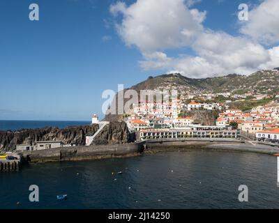 Guardando attraverso Camara de Lobos villaggio porto con faro su sperone roccioso in bella giornata di sole spting Madeira Portogallo UE Foto Stock