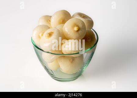 Piccole cipolle piatte (in Italia dette cipolle borettane) in una ciotola di vetro su sfondo bianco Foto Stock