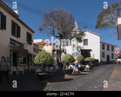 Ammira lungo Largo do Poco una delle strade principali dell'incantevole villaggio di pescatori di Camara do Lobo Madeira Portogallo UE con caffè e ristoranti all'aperto Foto Stock