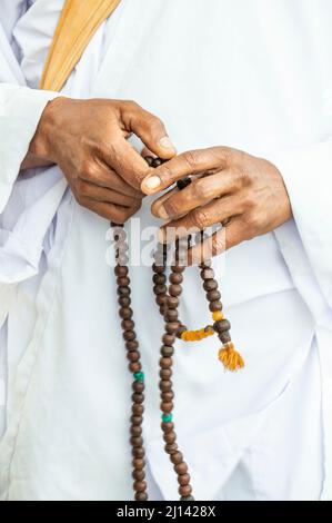 perle di preghiera, mani maschio closeup che tengono un rosario o perle di preghiera con fuoco selettivo sul bianco. mani di un uomo che prega con il rosario in medio oriente o Foto Stock
