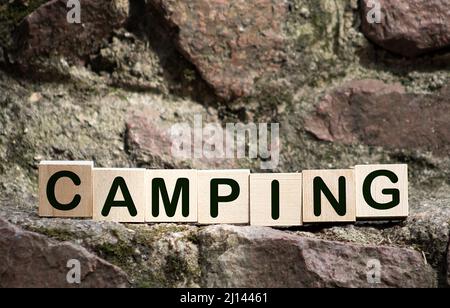 Parola di campeggio su un segno cubo di legno con uno sfondo sfocato di un campeggio in estate Foto Stock