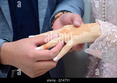 Uno sposo arabo indossa l'anello di nozze della sposa Foto Stock