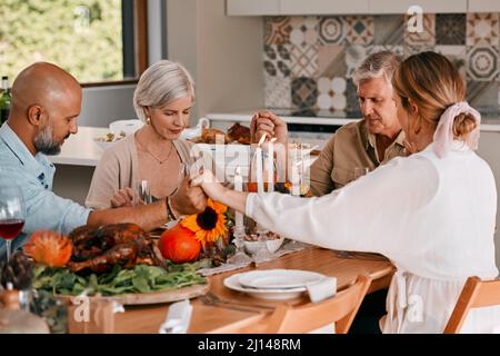 Che siamo grati per i buoni amici di tutti i giorni. Shot di un gruppo di amici maturi che si uniscono in preghiera prima di avere un pasto del Ringraziamento. Foto Stock