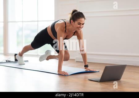 Donna allegra facendo l'esercitazione degli arrampicatori di montagna del corpo della croce Foto Stock