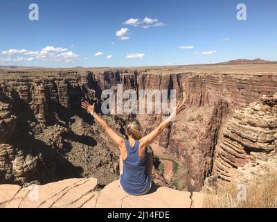 Una ragazza tedesca seduta con le braccia sul bordo di un canyon e godendo la vista. Foto Stock