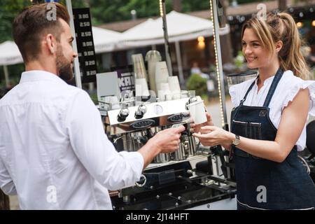 Bella donna barista che vende caffè al cliente Foto Stock