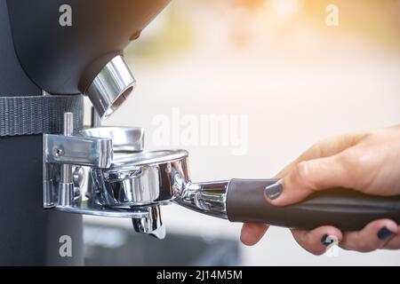 Il barista macina i chicchi di caffè nel portafiltro Foto Stock