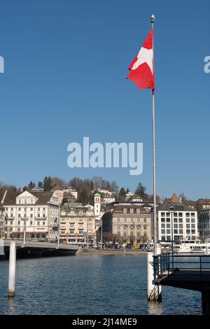 Lucerna, Svizzera, 10 marzo 2022 la bandiera svizzera sventola al vento sul lungomare del lago di Lucerna Foto Stock