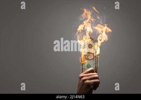 Bruciare il dollaro americano tenuto da una mano Foto Stock
