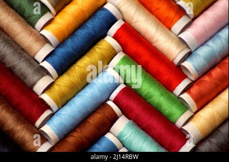 le bobine di filo da cucito multicolore giacciono in un modello a spina di pesce Foto Stock