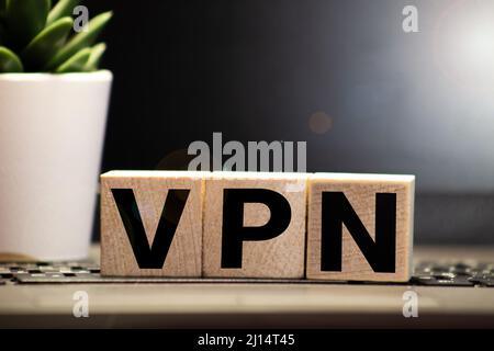 VPN Virtual Private Network scritto su un cubo di legno davanti a un laptop Foto Stock