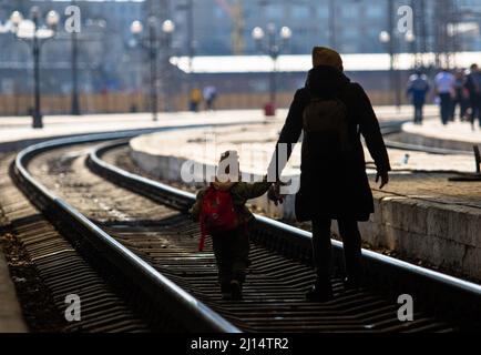 Lviv, Ucraina. 22nd Mar 2022. Una madre attraversa i binari del treno con il bambino dopo l'arrivo alla città di Lviv in treno. Mentre la guerra in Ucraina continua la gente fugge dalla violenza in treno che viene a Lviv o che viaggia verso la Polonia. (Foto di Ty ONeil/SOPA Images/Sipa USA) Credit: Sipa USA/Alamy Live News Foto Stock