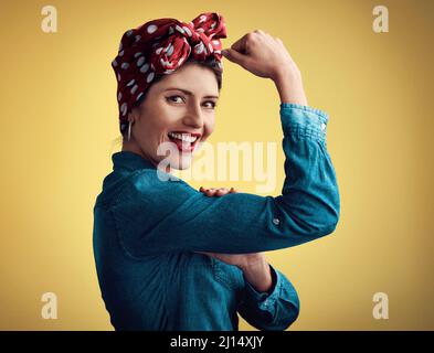 Chi dice che le donne non possono essere forti. Ritratto di studio di una giovane donna attraente che flette il suo bicep mentre si trova su uno sfondo giallo. Foto Stock
