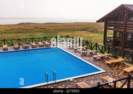 La pioggia incredibilmente pesante e il vento veloce e duro rovinano il caldo e soleggiato clima estivo nella base tranquilla con piscina per una vacanza attesa a lungo Foto Stock