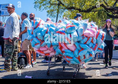 NEW ORLEANS, LA, USA - 20 MARZO 2022: Il fornitore di caramelle in cotone spinge il carrello sovraccaricato attraverso la folla in attesa della sfilata indiana del Mardi Gras la Super Domenica Foto Stock