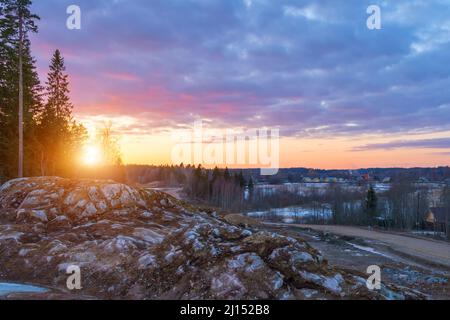 Bellissimo tramonto rosso arancio nel cielo sopra le scogliere di montagne e alti pini, pittoresche nuvole illuminate dal sole Foto Stock