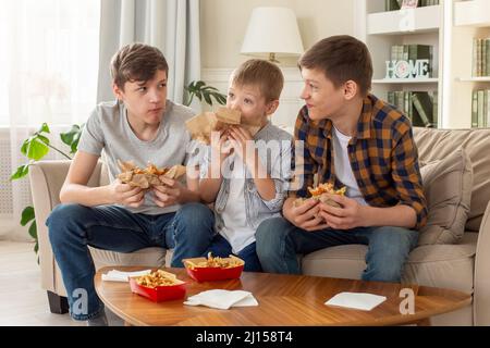 Un felice tre ragazzi adolescenti, mangiare fast food Foto Stock