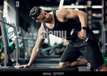 Giovane Muscle Middle Eastern Man allenarsi con Dumbbell alla moderna palestra Foto Stock