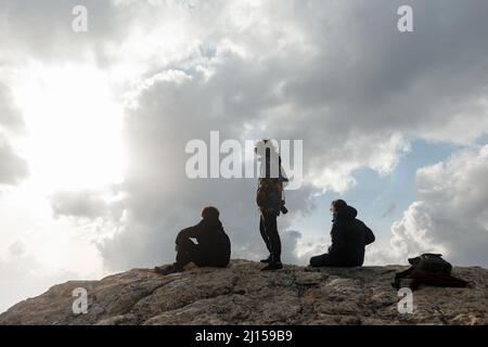 Tre amici maschi che si godono una vista panoramica sulla cima di una montagna in una giornata nuvolosa in Spagna Foto Stock