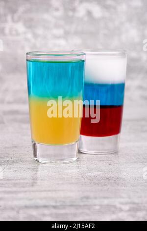 Due cocktail nei colori delle bandiere russe e ucraine su sfondo grigio Foto Stock