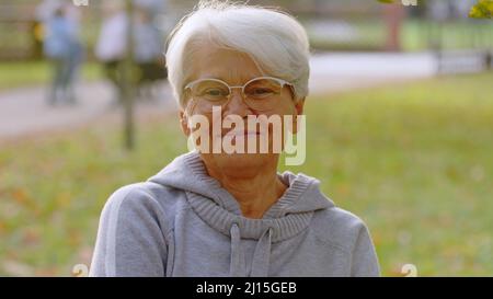 Ritratto di anziani caucasici donna grigio capelli e occhiali nel parco fuoco selettivo . Foto di alta qualità Foto Stock