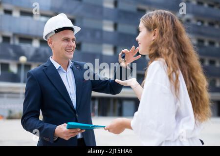 Builder che dà le chiavi al cliente dopo la conclusione del contratto di firma Foto Stock