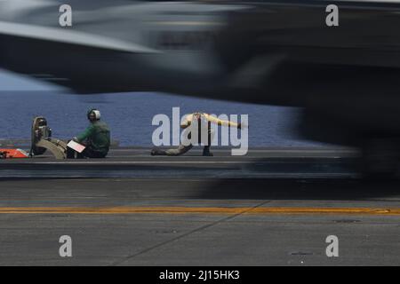 Il MAR DELLE FILIPPINE (21 marzo 2022) il Lt. Caleb Derrington, da Batesville, Ark., dirige un F/A-18E Super Hornet, assegnato ai 'Tophatters' di Strike Fighter Squadron (VFA) 14, sul ponte di volo del vettore aereo di classe Nimitz USS Abraham Lincoln (CVN 72). Abraham Lincoln Strike Group è in fase di implementazione pianificata nell'area delle operazioni della flotta USA 7th per migliorare l'interoperabilità attraverso alleanze e partnership, fungendo da forza di risposta pronta a supportare una regione indopacifica libera e aperta. (STATI UNITI Foto Navy di Sint. Di comunicazione di massa Seaman Aprentice Julia Brockman) Foto Stock