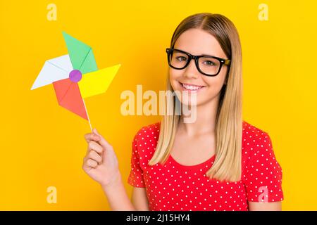 Foto di giovane bella ragazza buon umore tenere carta spinner mulino isolato su sfondo giallo Foto Stock