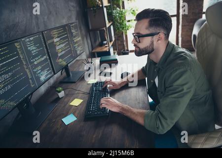 Profilo Vista laterale ritratto di attraente concentrato intellettuale ragazzo nerd supporto tecnico digitando html al lavoro workstation indoor Foto Stock