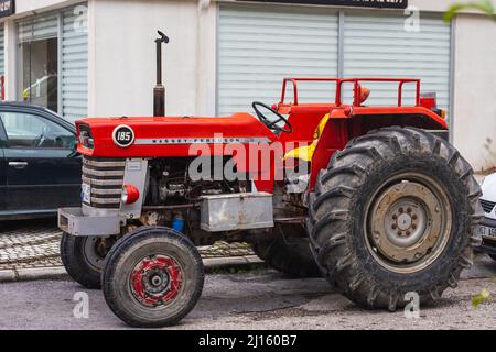 Side; Turchia – Marzo 03 2022: Il vecchio trattore rosso del marchio Massey Ferguson è parcheggiato in strada in una calda giornata estiva sullo sfondo di un Foto Stock