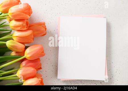 Tulipani arancioni freschi e spazio vuoto per la lettera su sfondo bianco con spazio per il testo. Biglietto d'auguri di primavera per il giorno delle madri. Foto Stock