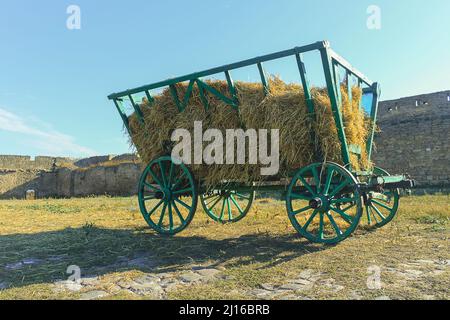 Un carretto di legno verde con fieno sullo sfondo delle pareti in pietra della fortezza di Belgorod-Dnestrovskiy Akkerman. Castello medievale vicino al mare. FORTIF Foto Stock