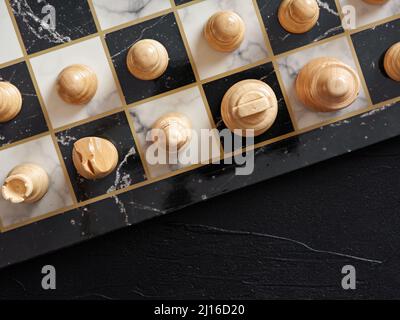 Vista dall'alto della scacchiera con pezzi su sfondo nero. Foto Stock
