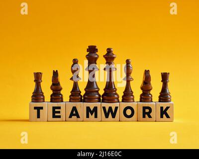 La parola lavoro di squadra su cubi di legno con pezzi di scacchi diversi. Concetto di strategia per il lavoro di squadra e la diversità aziendale. Foto Stock
