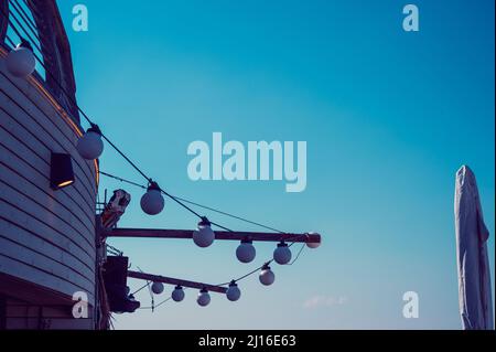 lampade bianche sotto forma di palline appendono sulla strada contro il cielo blu Foto Stock