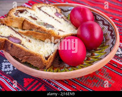 fette di pane dolce pasquale tradizionale o cozonac e uova decorate traditional, piatto pasquale rumeno, su stoffa da tavola Foto Stock