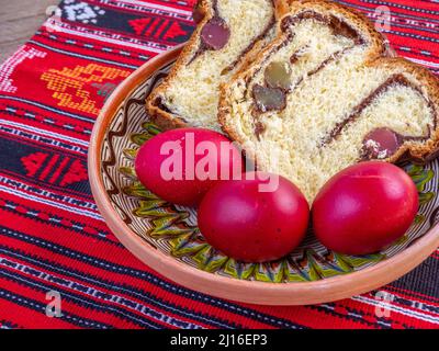 fette di pane dolce pasquale tradizionale o cozonac e uova decorate traditional, piatto pasquale rumeno, su stoffa da tavola Foto Stock