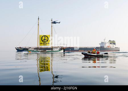 Fehmarn, Germania. 23rd Mar 2022. Gli attivisti dell'organizzazione ambientalista Greenpeace dimostrano con il banner "Stop Fomettendo la guerra!" Di fronte a una nave che trasporta petrolio russo sul Mar Baltico. Credit: Frank Molter/dpa/Alamy Live News Foto Stock