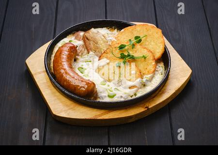 Frittelle di patate con salsiccia tedesca fritta e fette di pancia di maiale Foto Stock