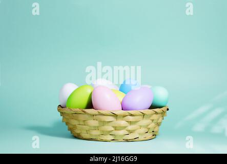 Sfondo di Pasqua. Una collezione di uova di Pasqua in colori pastello in un cestino su sfondo blu-verde, con ombre e luce dure. Foto Stock