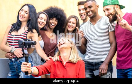 Giovani amici multirazziale prendere selfie con cellulare smart phone e stabilizzatore gimbal - Friendship concetto con gente milleniale divertirsi insieme Foto Stock