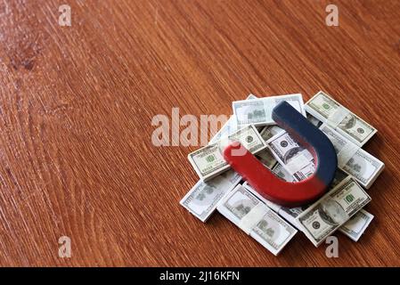 Magnete in cima a mucchio di soldi. Sfondo in legno. Spazio di copia per il testo. Concetto di business e finanza Foto Stock